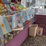 img data-src="image.png" alt="Fachada del local comercial La Goleta luciendo grandes banderas argentinas en sus ventanas y accesos principales."
