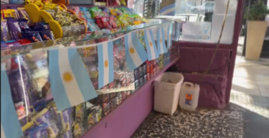 img data-src="image.png" alt="Fachada del local comercial La Goleta luciendo grandes banderas argentinas en sus ventanas y accesos principales."